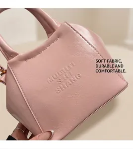 Detail of pink faux leather texture with MUEHTI embossed lettering on crossbody bag