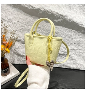 Détail du sac seau jaune citron avec texture litchi et breloque coeur en métal