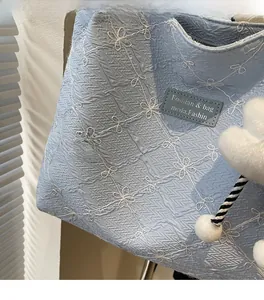 Close-up of light blue floral embroidered tote bag showing seersucker fabric texture