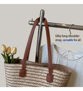Detail of handwoven tote bag with beige striped texture and brown leather shoulder straps