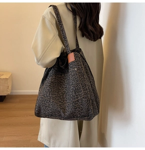 Detail of leopard print canvas tote bag featuring outer pocket and metal rivet accents