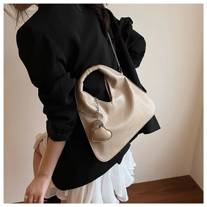 Detail of beige pleated leather handbag with silver chain and heart charm decoration