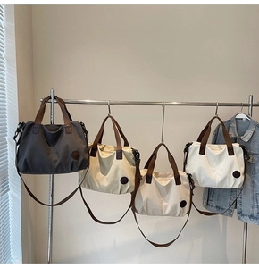 Detail view of large canvas tote bags in four neutral colors on a display rack