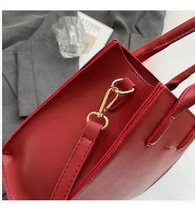 Close-up of red leather handbag with gold rotating lobster clasp and stitching details