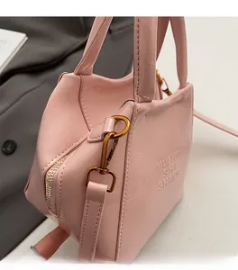 Detail of pink patent leather handbag featuring logo embossing and gold-tone metal hooks
