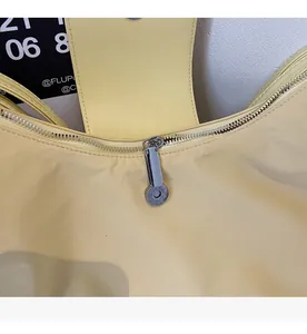 Detail of smooth silver zipper on a light yellow soft nylon shoulder bag for daily commute