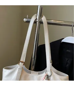 Close-up of white PU tote bag showing smooth adjustable shoulder straps and metal buckle