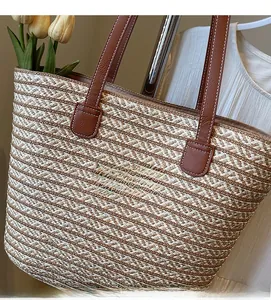 Detail of paper rope woven tote with brown leather strap and contrast white stitching