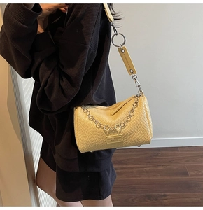 Detail view of yellow woven texture boston bag with metal flower chain and wide strap