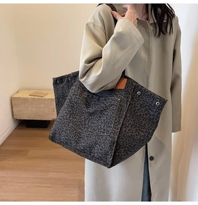 Detail of leopard print canvas tote bag with leather label and metal rivet accents