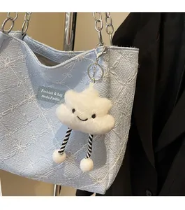 Close-up of a plush white cloud charm with striped legs hanging on a tote bag