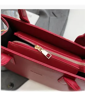 Detail of red square tote bag showing smooth golden metal zipper and PU leather texture
