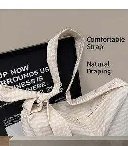 Detailed shot of beige pinstripe tote bag featuring adjustable bow-tie shoulder straps