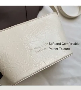 Gros plan du sac seau blanc crème avec texture plissée rétro et lettrage mode embossé