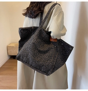 Detail of leopard print canvas tote bag featuring a spacious front pocket and metal snaps