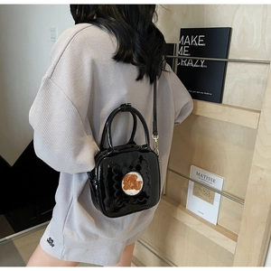Detail of black patent leather crossbody bag with cute bear window and adjustable strap