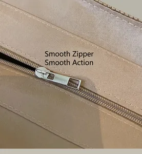 Detail of silver metal zipper on beige woven shoulder bag showing smooth texture