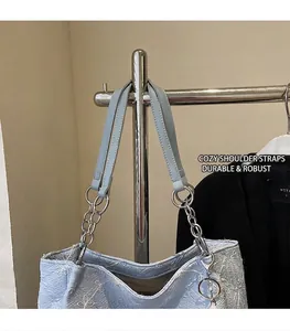 Detailed embroidery of white flowers on light blue tote bag with chain strap