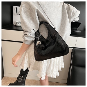 Close-up of black pleated faux leather bag with silver chain strap and heart charm