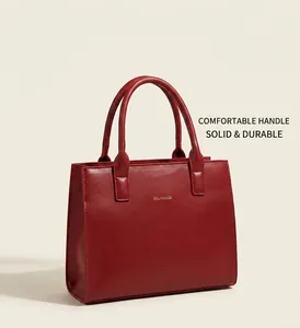 Detail view of red leather tote bag featuring golden Solar&Miss logo and dual handles