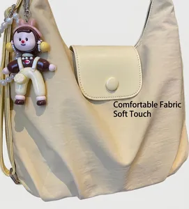 Detailed texture of beige canvas tote featuring a doll pendant and pearl chain