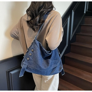 Detailed view of dark blue denim tote bag featuring asymmetric design and silver metal buttons