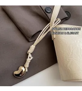 Détail du sac seau blanc avec texture plissée et charm pendentif en forme de cœur en métal