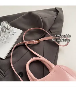 Detailed shot of soft pink leather handbag with adjustable strap on a gray blazer