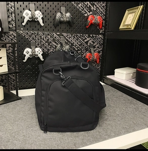 Close-up of black nylon travel bag featuring side zipper pocket and adjustable strap