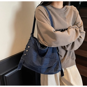 Detail of dark blue denim tote bag with silver studs and adjustable shoulder strap
