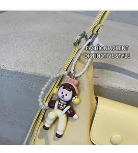 Detail of creative cartoon doll pendant with pearl chain on a yellow canvas tote bag