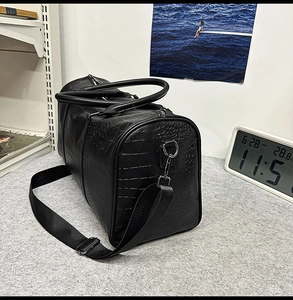 Detail view of black crocodile pattern faux leather travel bag with adjustable strap