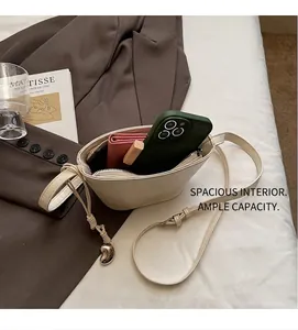 Vue détaillée de l'intérieur d'un sac seau blanc cassé avec accessoires et pendentif cœur doré