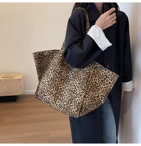 Close-up of leopard print canvas tote bag carried by a model in a black trench coat