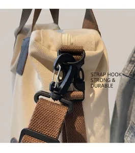 Detail of durable black plastic hook and brown woven shoulder strap on canvas tote bag