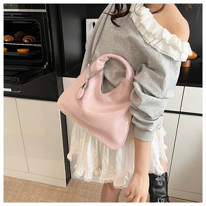 Detail of pink patent leather handbag with pleated texture and silver chain strap