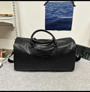 Detail of black faux leather travel bag featuring premium crocodile embossed texture