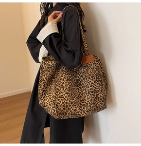 Detail of large leopard print canvas tote bag with leather tag shown on a model