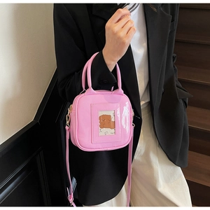 Detail of pink patent leather square handbag with transparent card slot and bear insert