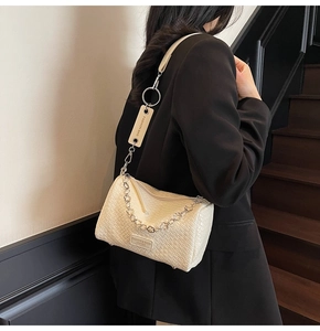 Detailed view of cream crossbody bag featuring woven texture and floral silver chain