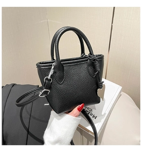 Close-up of black litchi pattern leather bucket bag with silver heart charm and strap