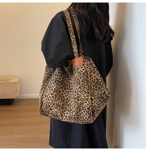 Detail of leopard print canvas tote bag featuring brown leather side trim and premium texture