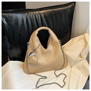 Detail of beige pleated leather bag with silver chain strap and heart charm