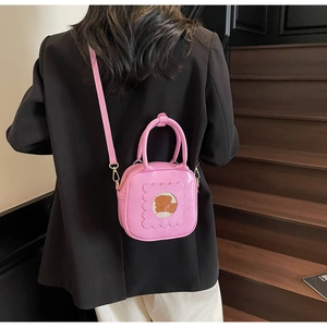 Pink glossy patent leather crossbody bag with cute bear window detail and shoulder strap