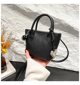 Détail du sac seau en cuir noir avec pendentif coeur et bandoulière réglable pratique