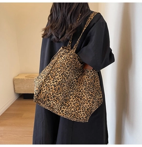 Detail of leopard print canvas tote bag featuring a side pocket with decorative metal rivets