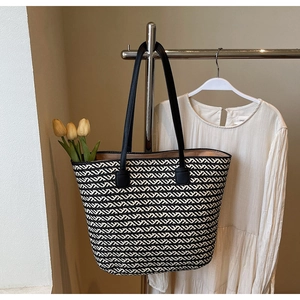 Detail of woven tote bag with black and white wave pattern and leather handles