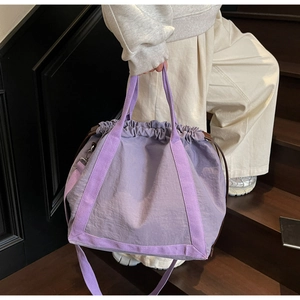 Detail van lichtpaarse tote bag met trekkoord over de schouder op een trap
