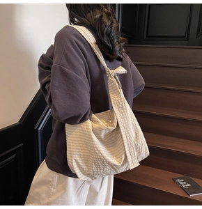 Close-up of beige plaid tote bag featuring a decorative knotted strap and fabric texture
