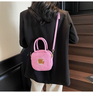 Pink crossbody bag with cute bear window pattern worn by a model on dark stairs